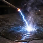 electrodo con punta incandescente con rayo saliendo desde la punta hacia un charco de agua
