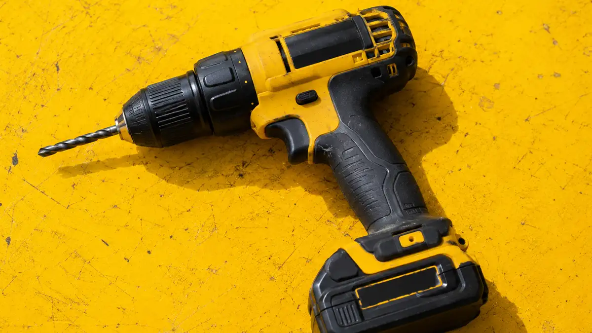 taladro inalámbrico amarillo sobre una mesa de taller amarilla